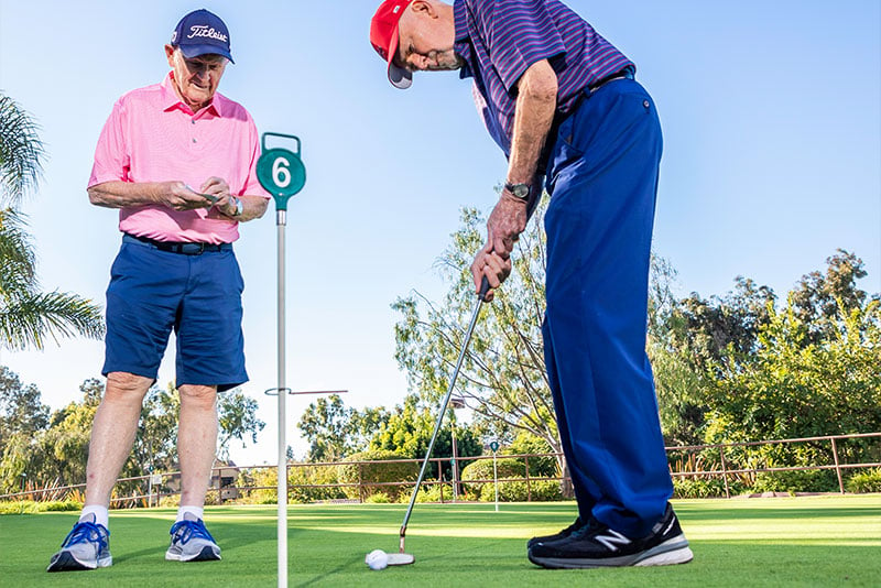 Two senior men practicing on putting green